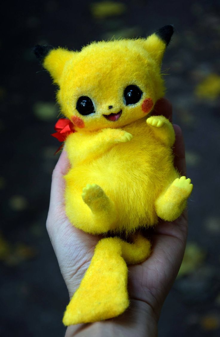 a hand holding a small yellow stuffed animal