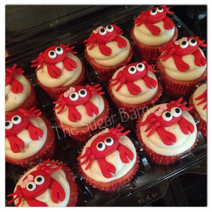 cupcakes decorated with red and white icing in the shape of crabs