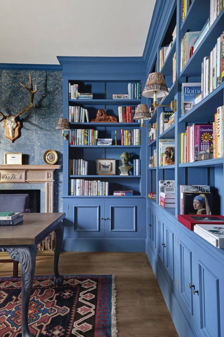 a room with blue bookshelves and a table in the center is full of books