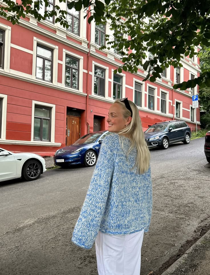 a woman walking down the street in front of a red building