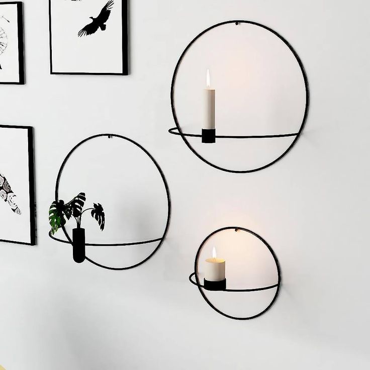 three circular metal wall sconces mounted on the wall with candles next to them