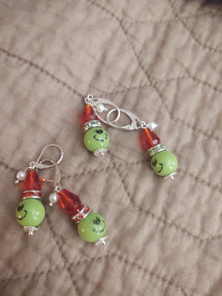 two green and red beaded earrings sitting on top of a bed