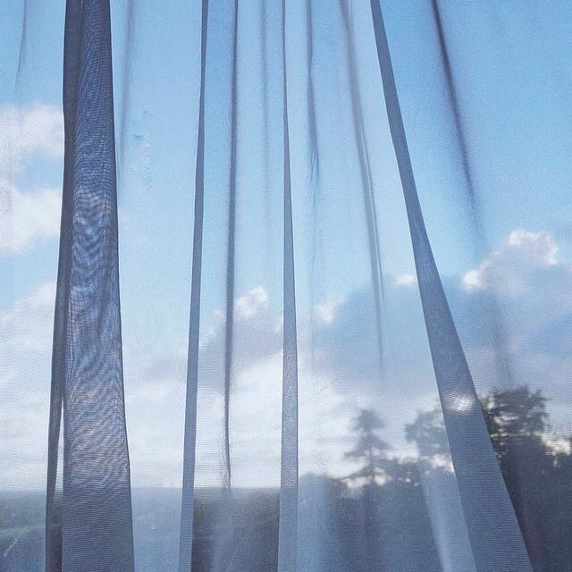 there is a cat sitting on the window sill looking out at the sky and clouds