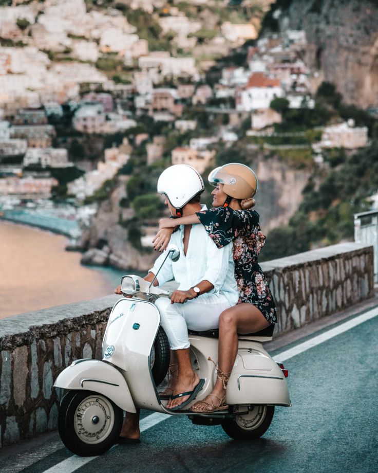 three people on a motor scooter in front of a scenic cityscape