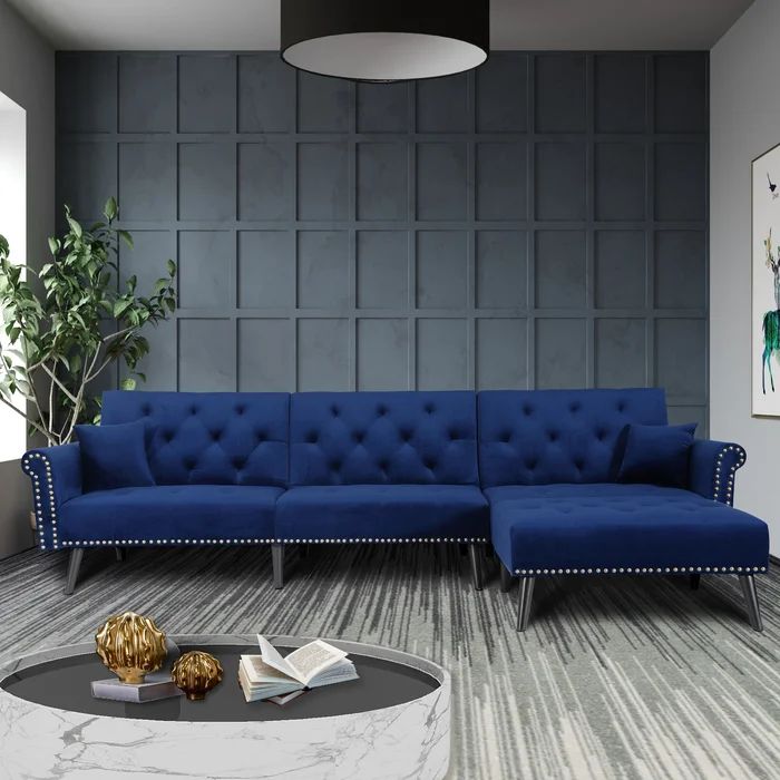 a black couch sitting on top of a wooden floor next to a table and potted plant