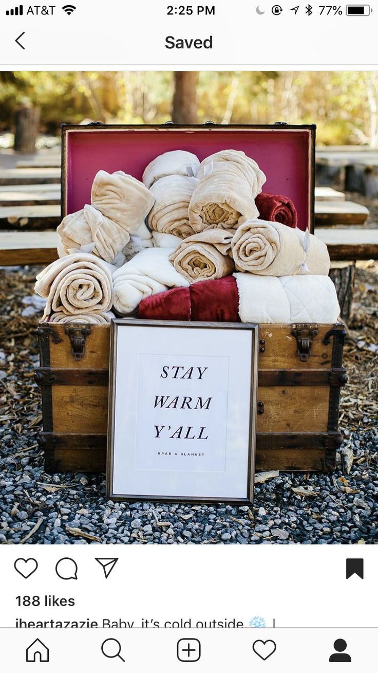 an open suitcase filled with towels on top of a gravel covered ground next to a sign that says stay warm y'all