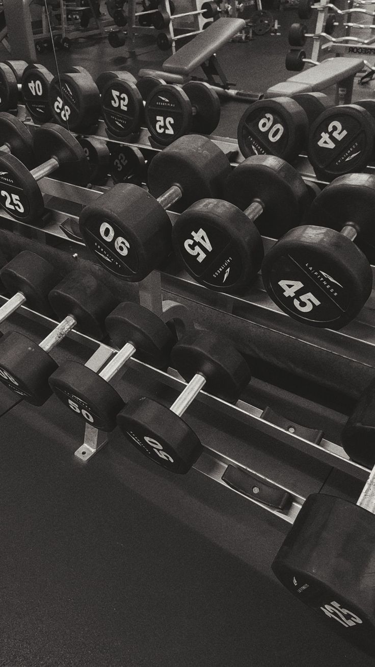 a row of black and white dumbbells with numbers on them in a gym