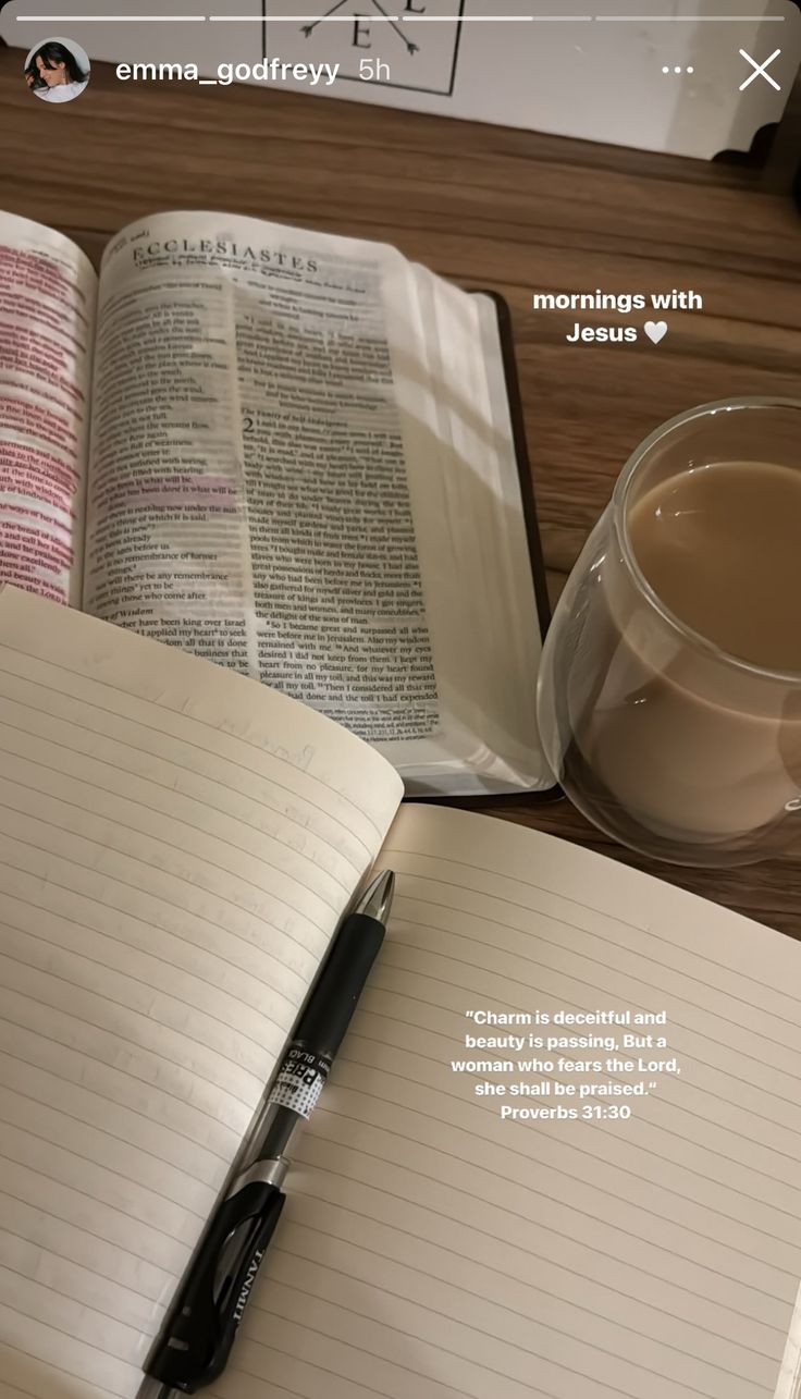 an open book next to a cup of coffee and a pen on a wooden table