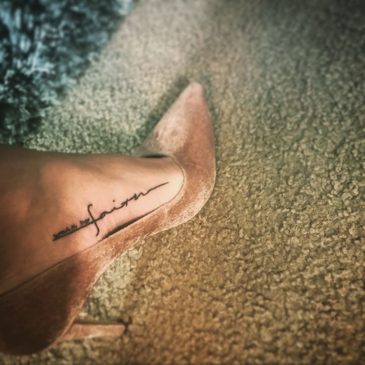 a woman's foot with the word faith written in cursive writing on it