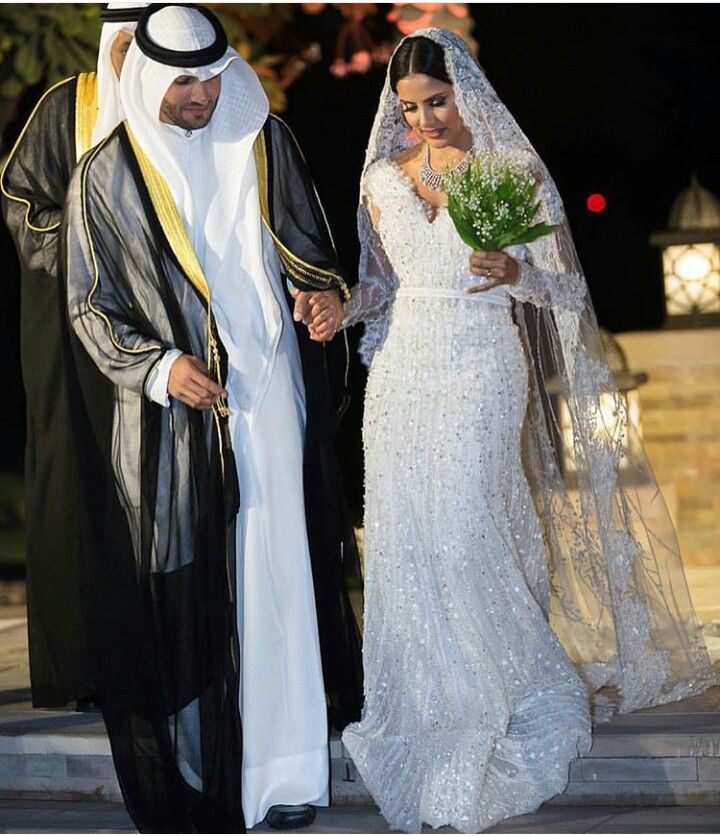 the bride and groom are dressed in traditional arabic garb for their wedding ceremony at night