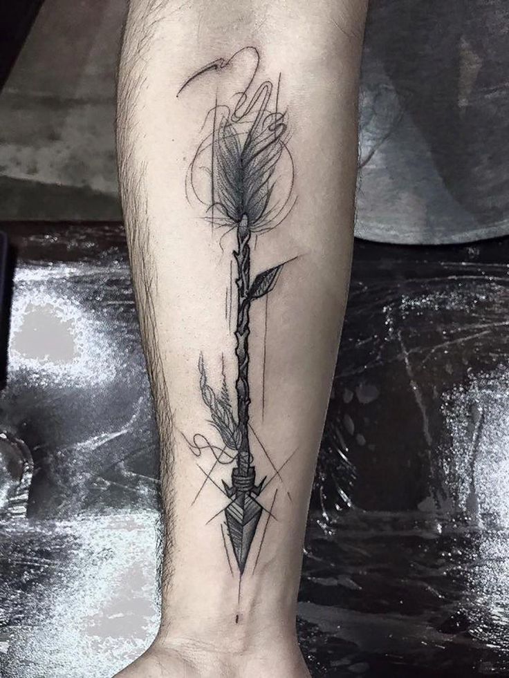 a tattoo on the leg of a man with an arrow and feathers in it,