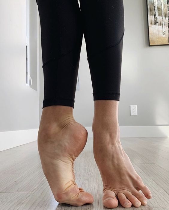 a person standing on top of a hard wood floor with their bare feet in the air