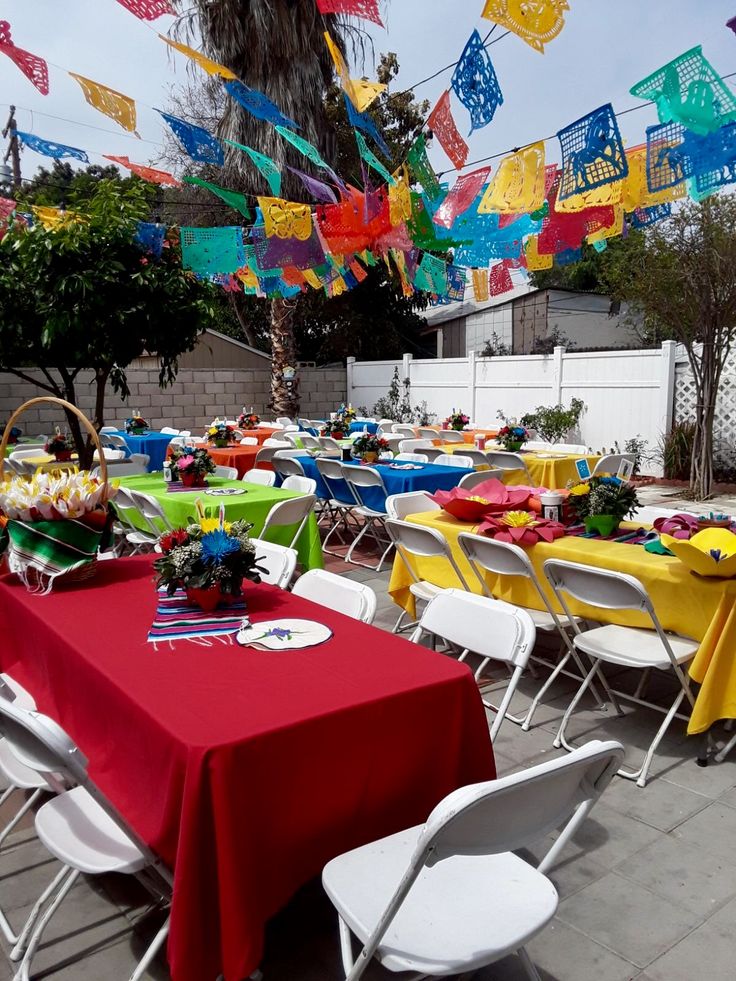 tables and chairs are set up outside with colorful flags hanging from the sky above them