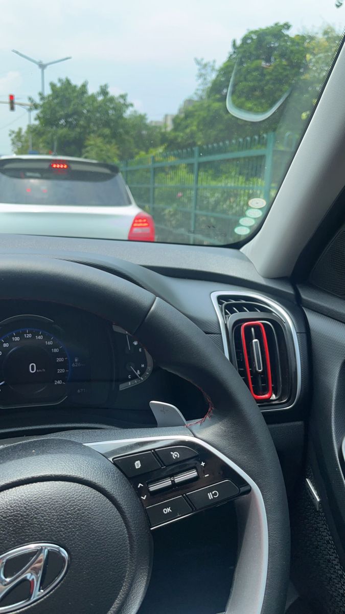 the interior of a car with dashboard lights and steering wheel controls in front of trees