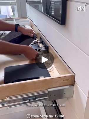 a person is working on an appliance in a kitchen with white cabinets and drawers