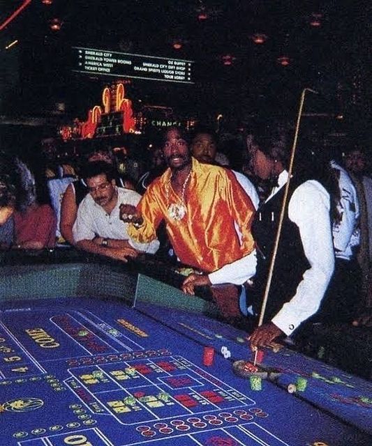 a man standing next to a rouleet in front of people at a casino