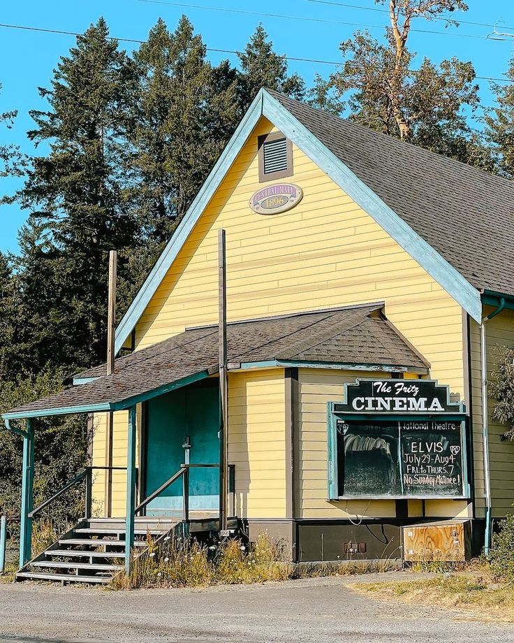 a small yellow building sitting next to a forest