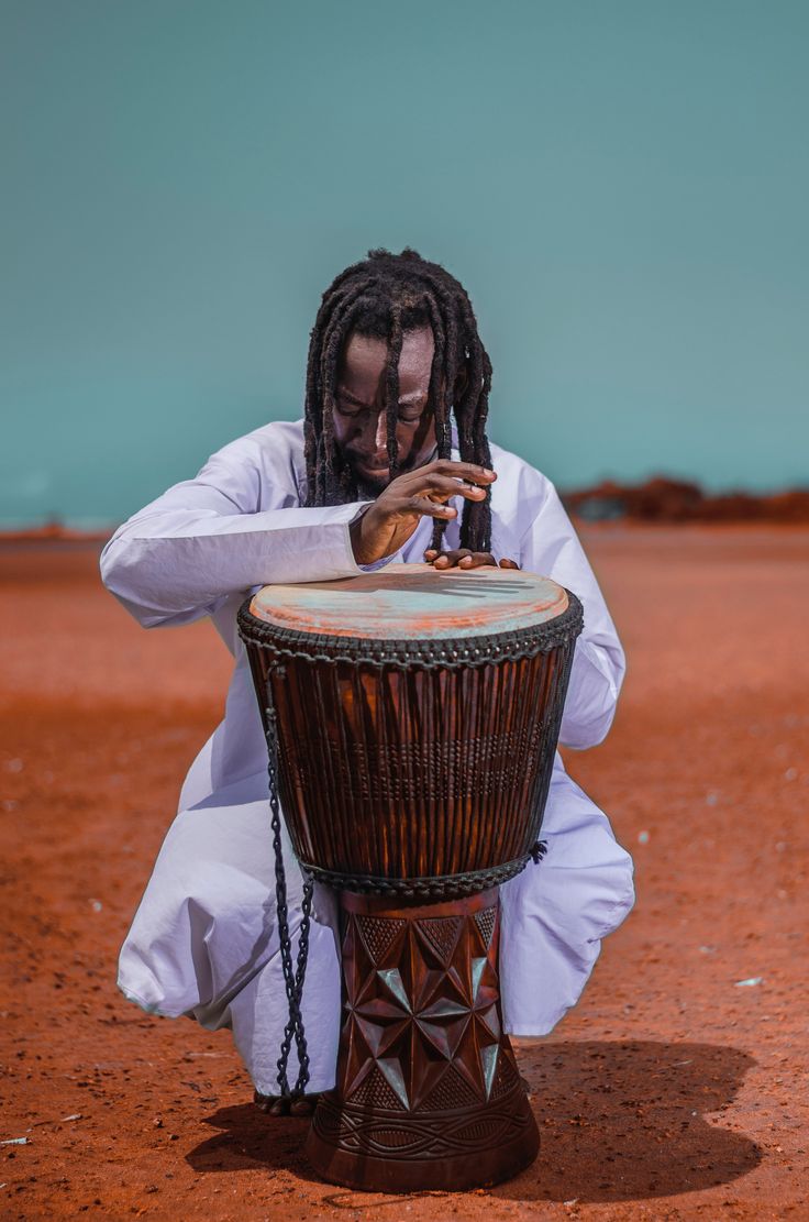 a man with dreadlocks sitting on top of a drum