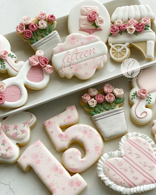 decorated cookies are arranged in the shape of letters and numbers, with pink flowers on them