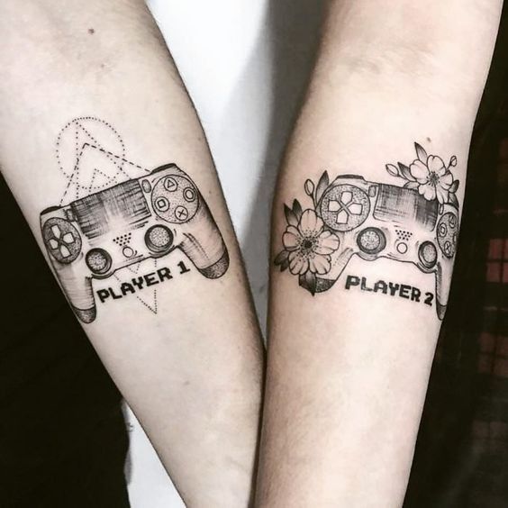 two people with tattoos on their arms holding video game controllers and playing games written in black ink