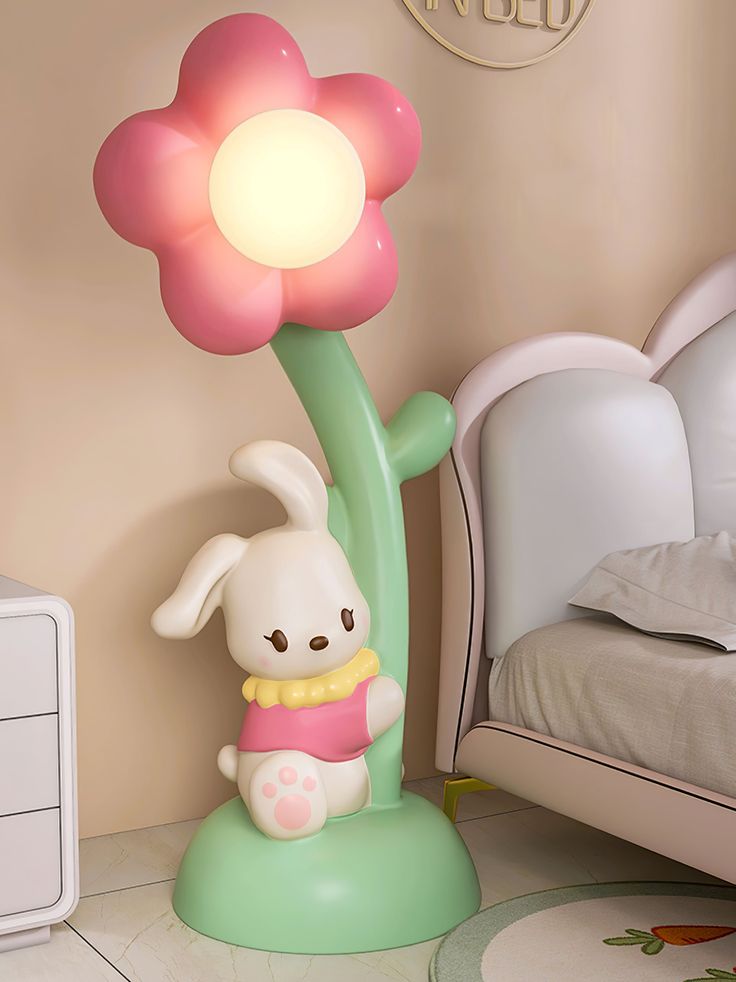 a lamp that is on top of a table next to a stuffed animal and flower