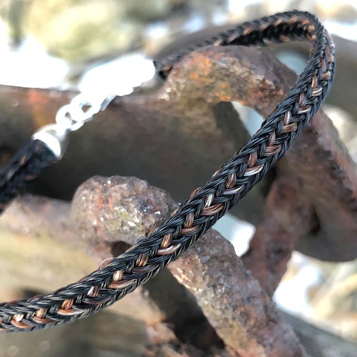 a braided leather bracelet sitting on top of rocks