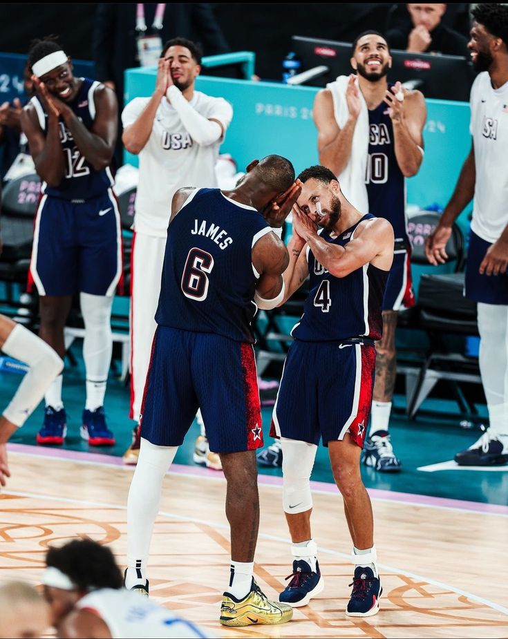 two basketball players are hugging each other while the rest of the team is clapping behind them