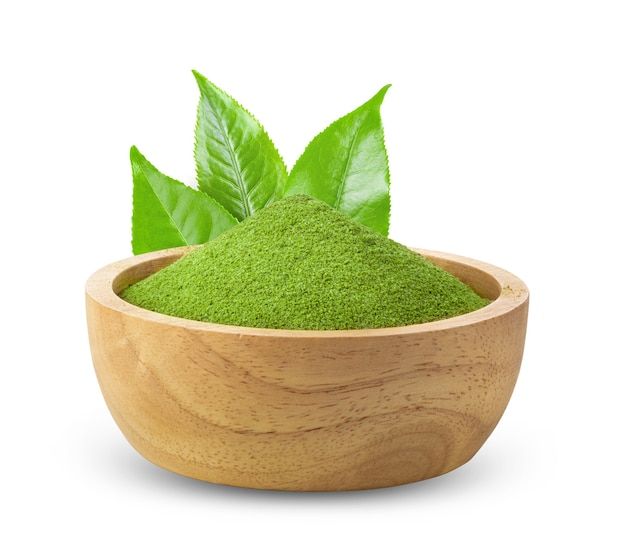 a wooden bowl filled with green powder and two leafy leaves on top of it