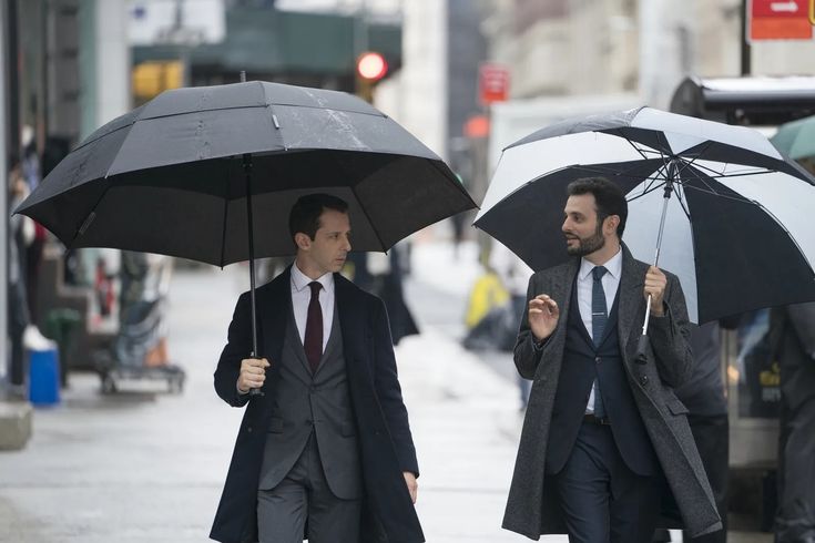 two men walking down the street holding umbrellas