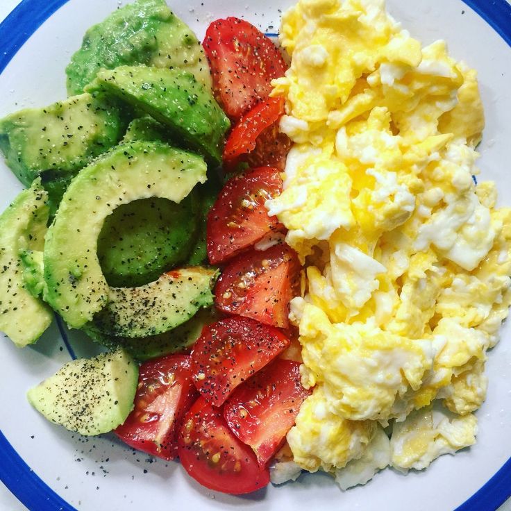 a plate with eggs, avocado, strawberries and other vegetables on it