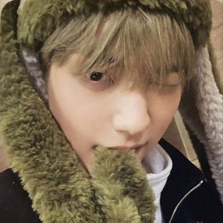 a young man wearing a furry hat and holding a stuffed animal in his mouth while looking at the camera