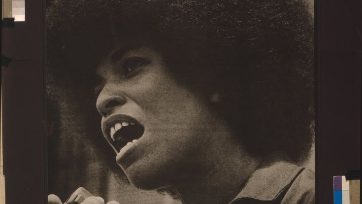 a black and white photo of a woman with an afro holding a microphone in her hand