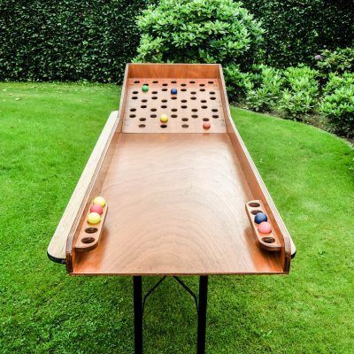 a wooden table with two game pieces on it in the middle of a grassy area