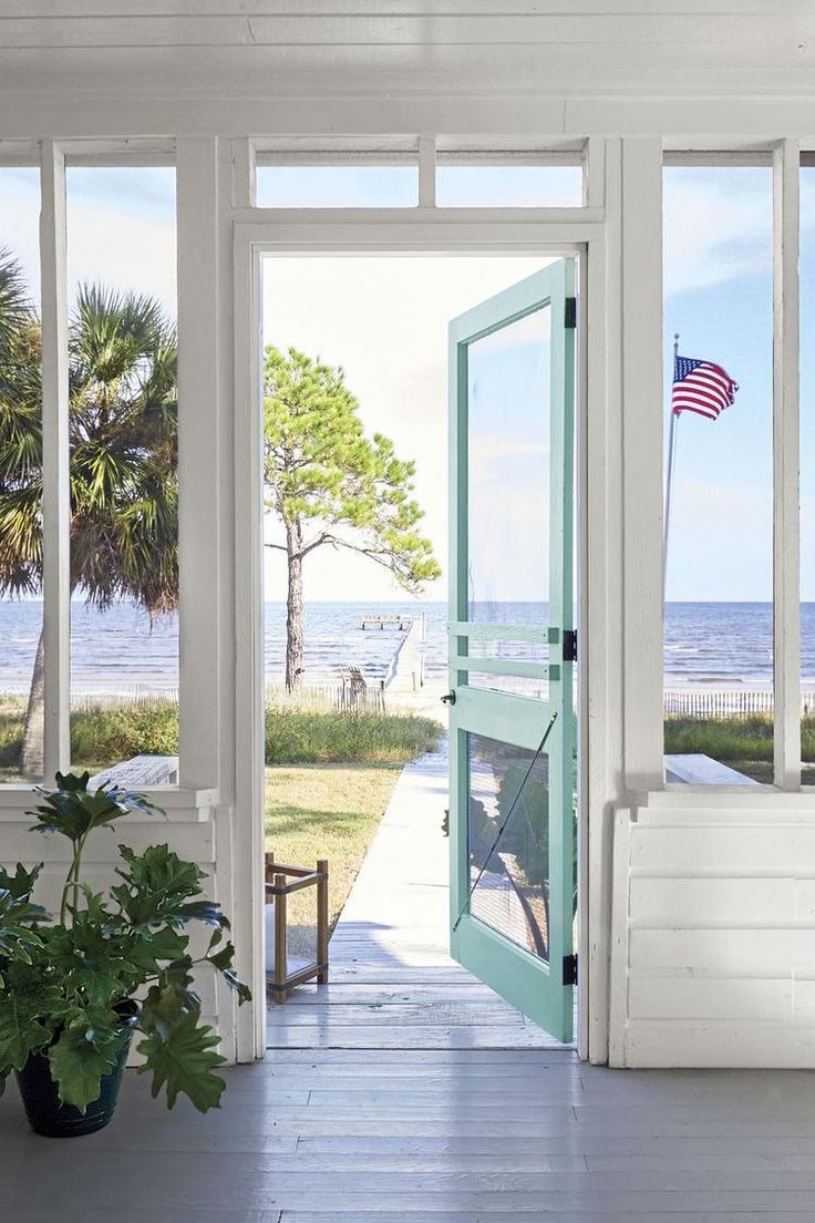 an open door leading to a porch with a view of the beach and ocean in the background