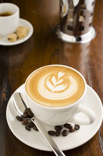 a cappuccino on a saucer with coffee beans