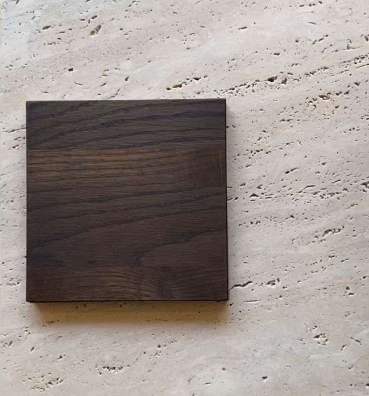 a square piece of wood sitting on top of a white floor next to a wall