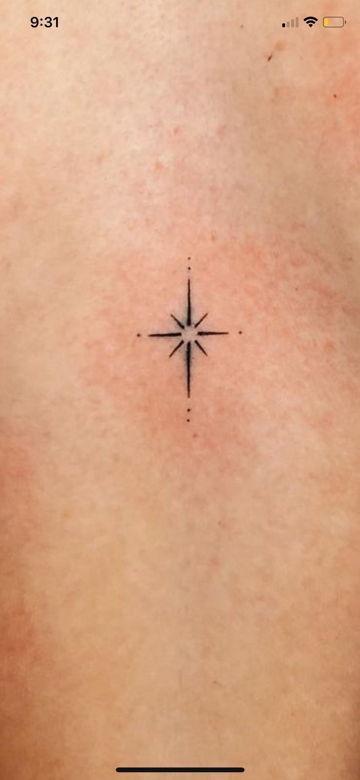 the back of a person's chest with a small star tattoo on it