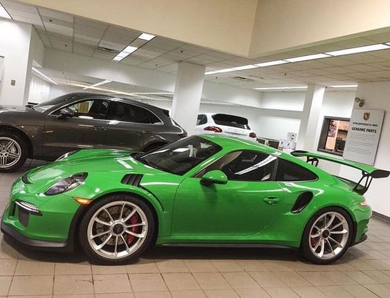 two green sports cars parked in a showroom