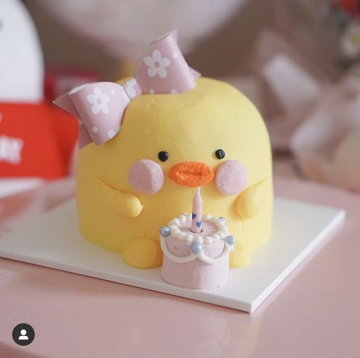 a cake shaped like a duck with a candle in its mouth