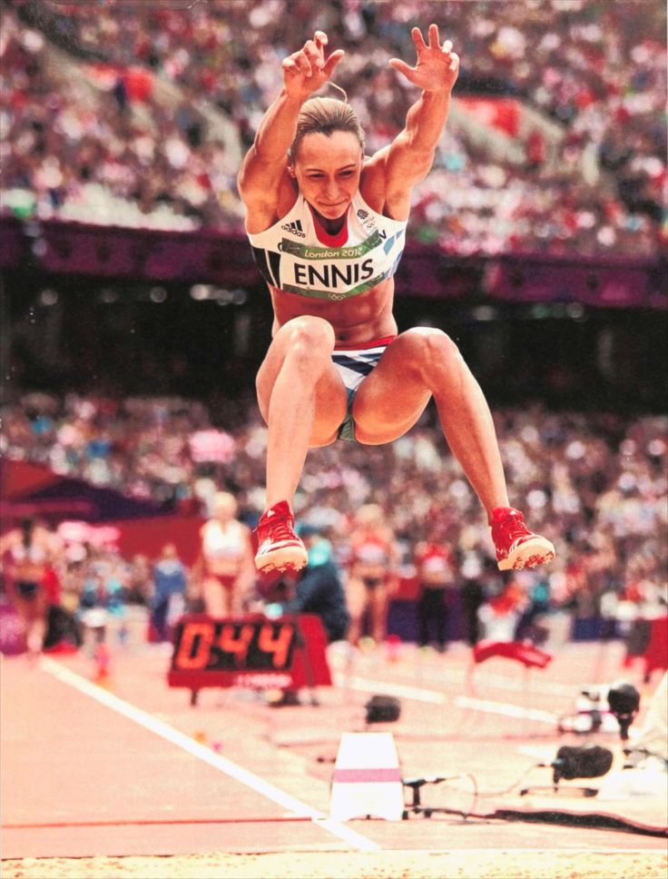 a woman jumping in the air on top of a track