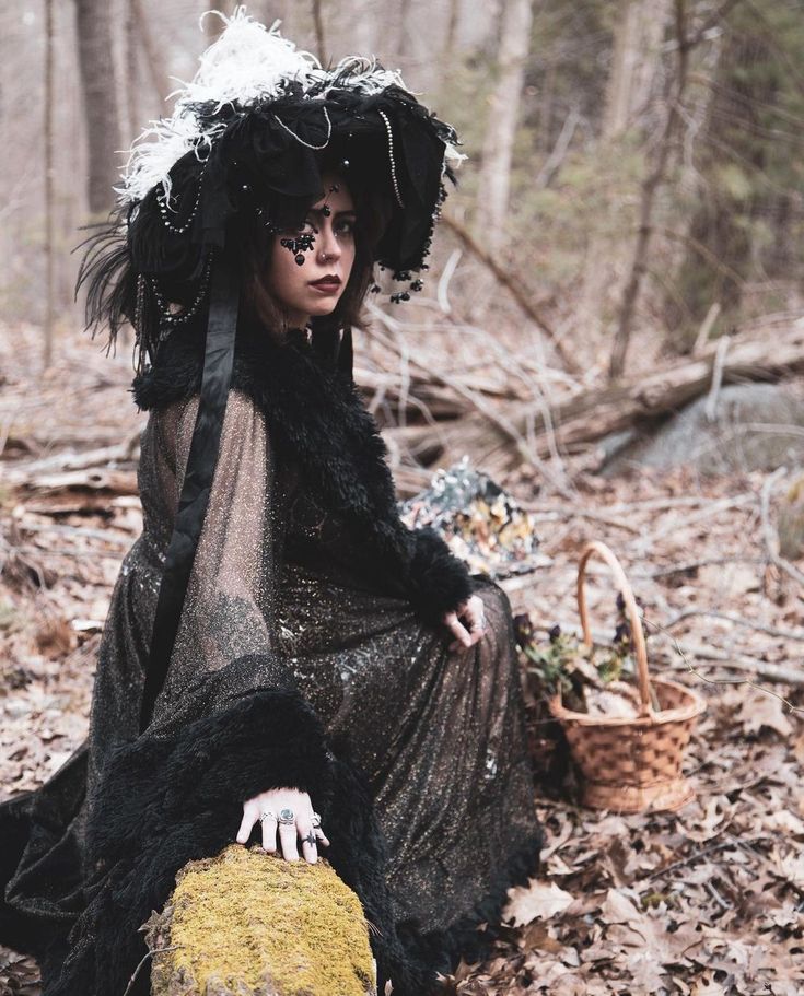 a woman sitting on the ground with a rock in her hand and wearing a hat