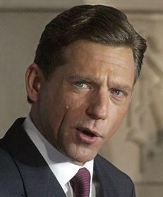 a close up of a person in a suit and tie looking at the camera with a serious look on his face