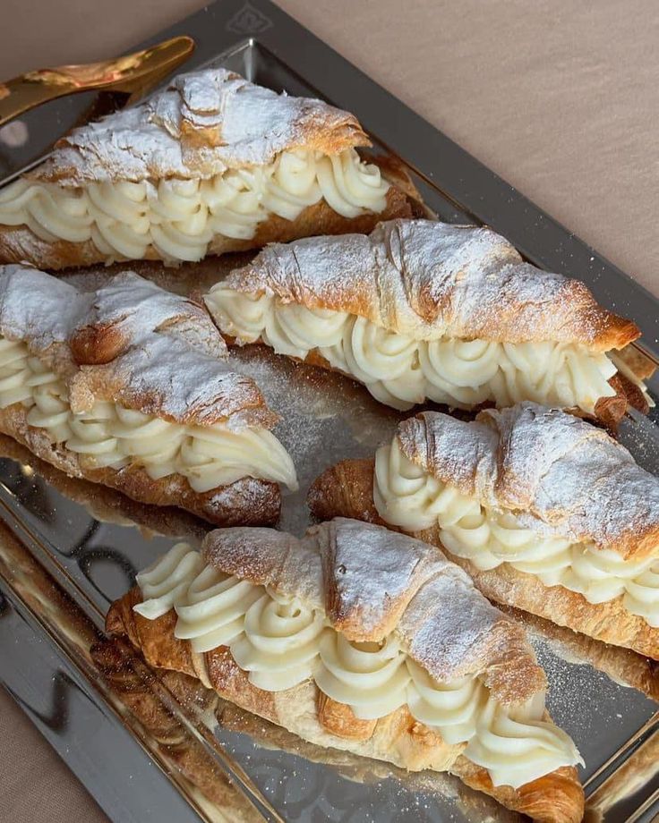 several pastries sitting on top of a pan covered in powdered sugar and icing