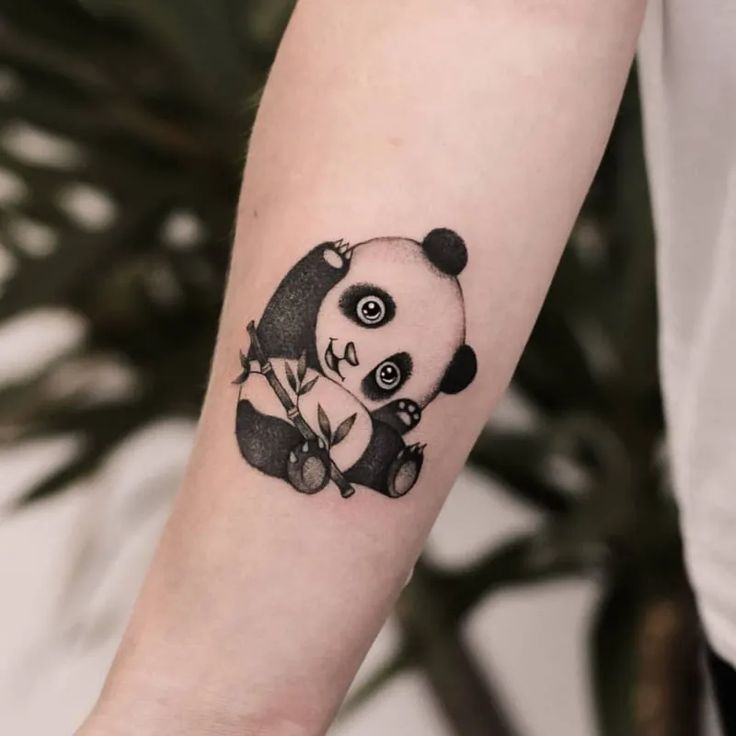 a small panda bear tattoo on the arm