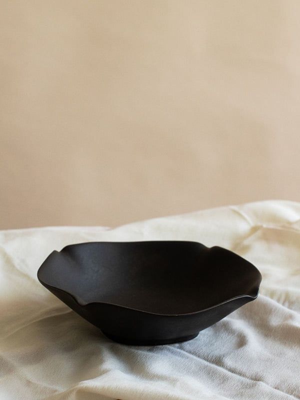 a black bowl sitting on top of a white sheet