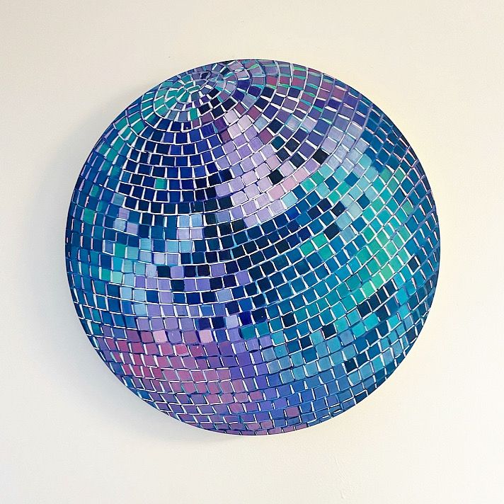 a blue and purple mirror ball on a white wall