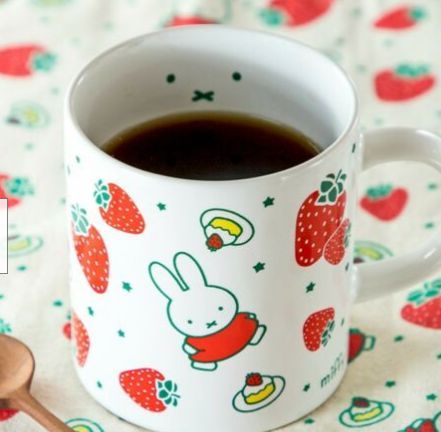 a cup of coffee with strawberries on it and a spoon next to the cup