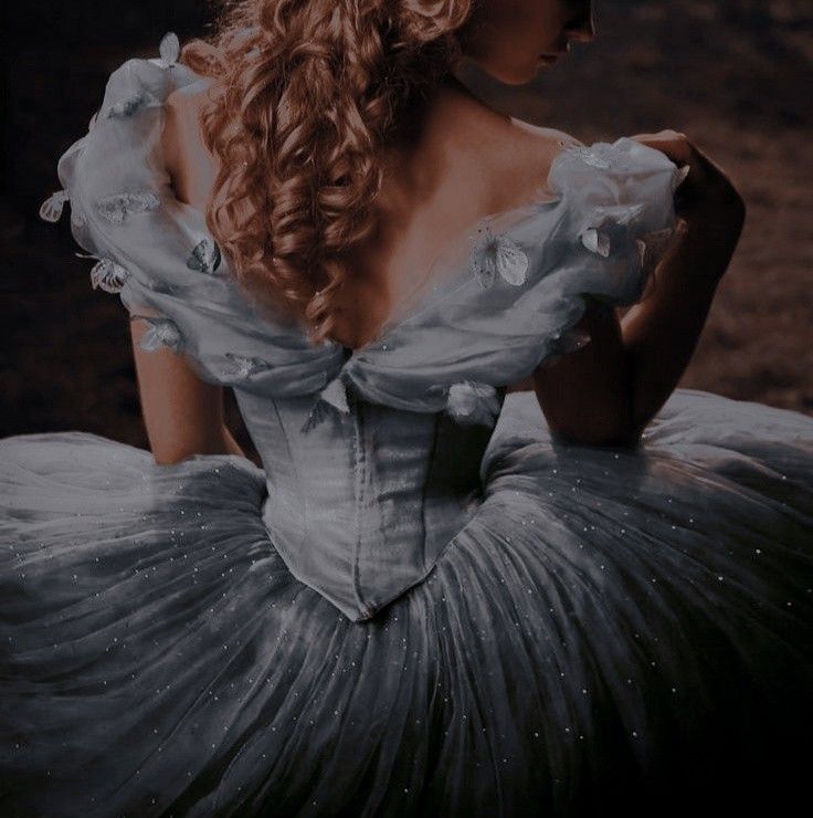 a woman in a dress sitting on the ground with her back turned to the camera