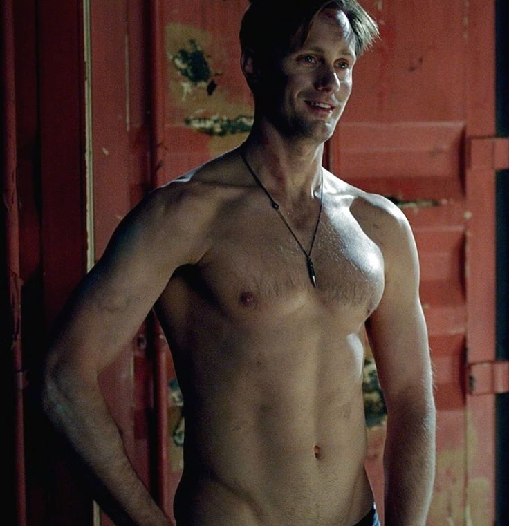 a man without a shirt standing in front of a red door with his hands on his hips