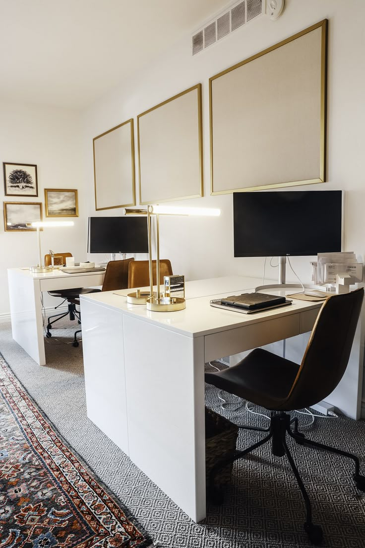 a desk with two computer monitors on it and a rug in front of the desk